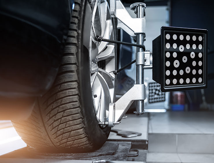 CLose-up car wheel indoors service maintenance repair center against laser sensor equipment diagnostics and 3d wheel alignment. Vehicle inside garage workshop for auto camber toe check fixing work L'équilibrage des pneus du véhicule